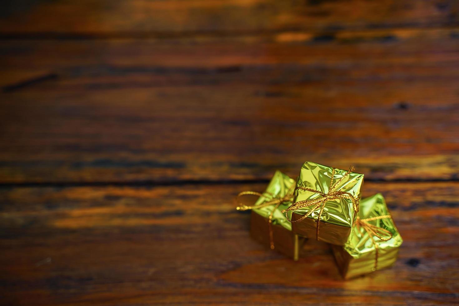 New Year and Christmas gift themed decorations on wooden background, consisting of a golden gift box.  shiny colored balls  Dried pine cones and small bells  free space for design photo