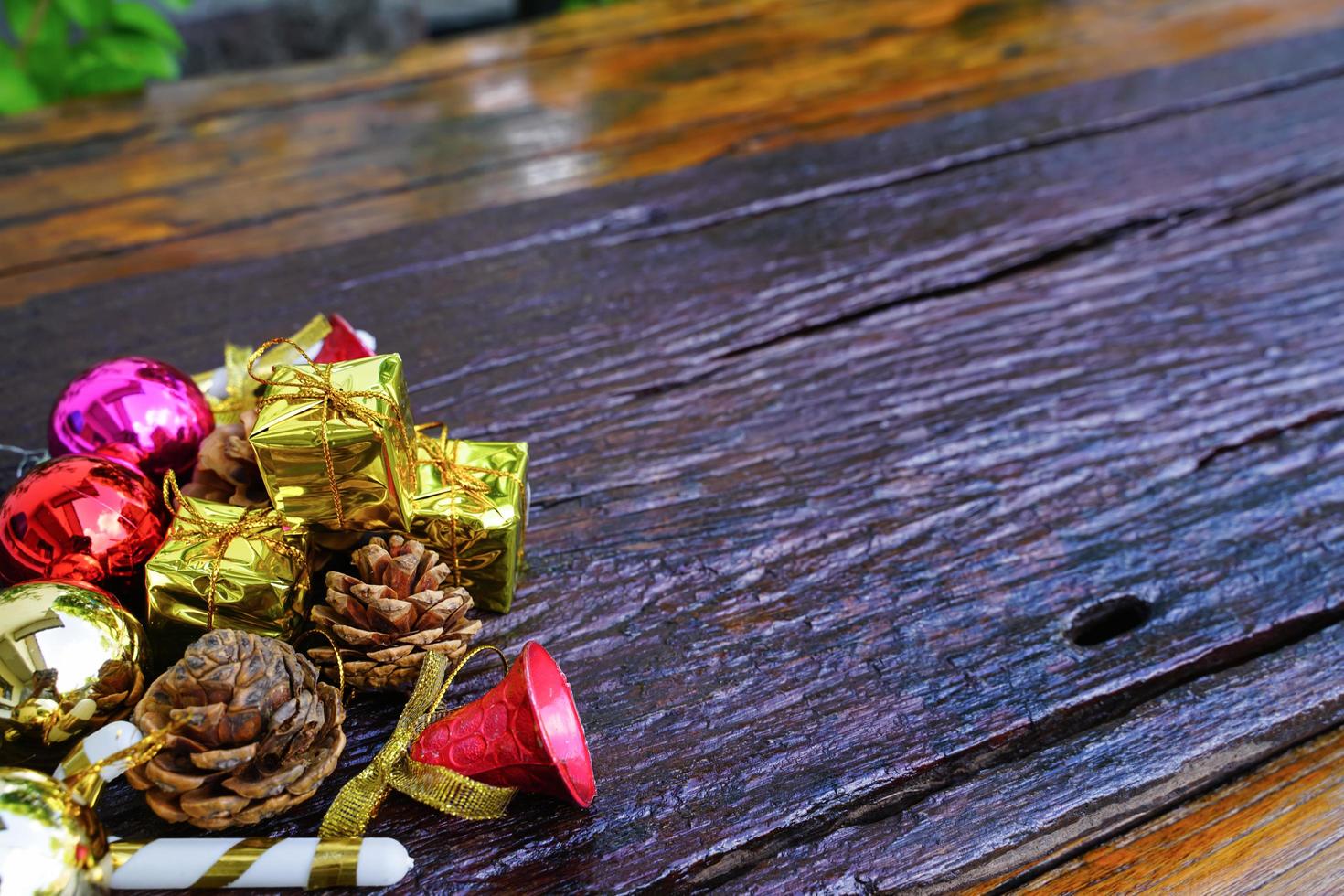 New Year and Christmas gift themed decorations on wooden background, consisting of a golden gift box.  shiny colored balls  Dried pine cones and small bells  free space for design photo