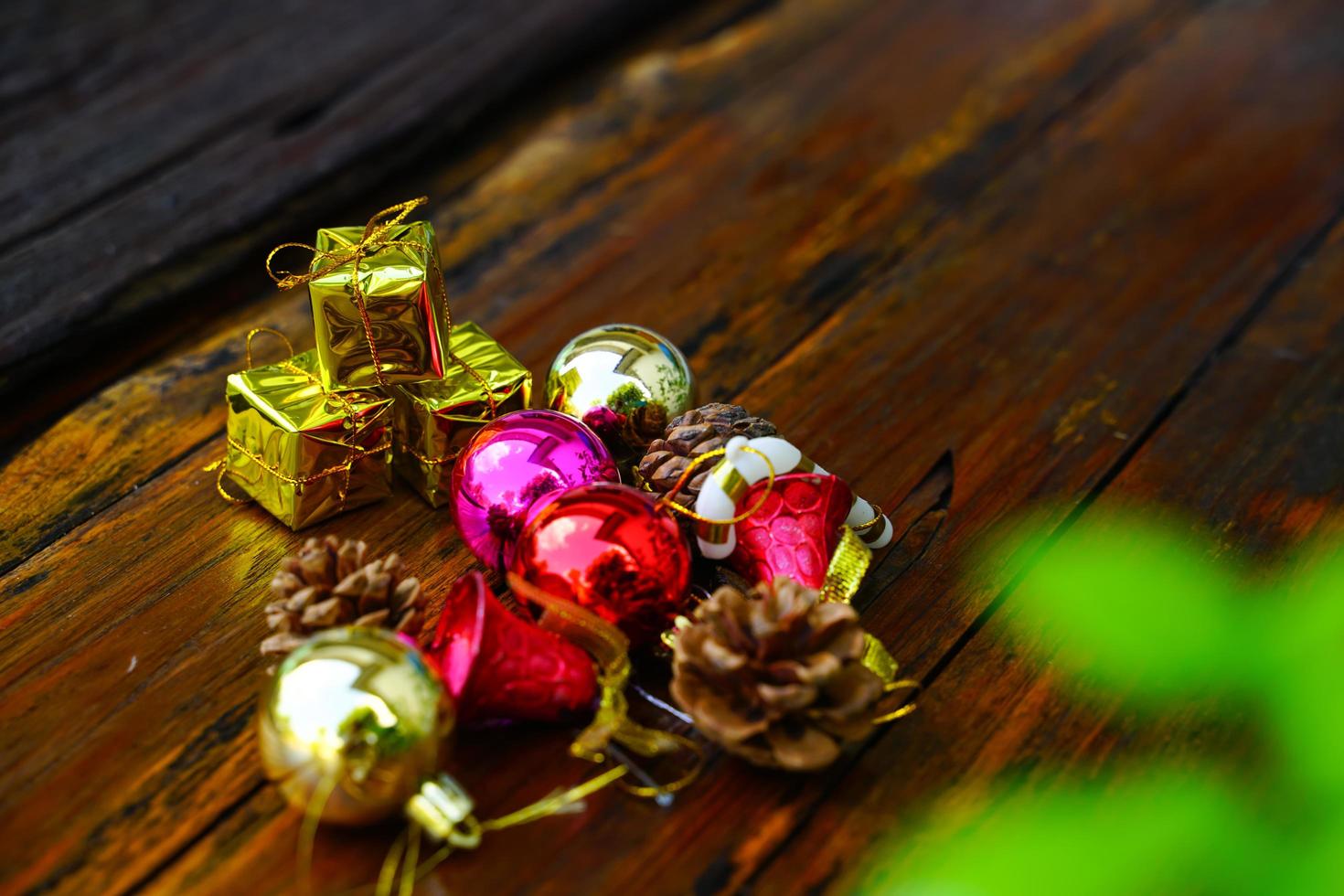 New Year and Christmas gift themed decorations on wooden background, consisting of a golden gift box.  shiny colored balls  Dried pine cones and small bells  free space for design photo