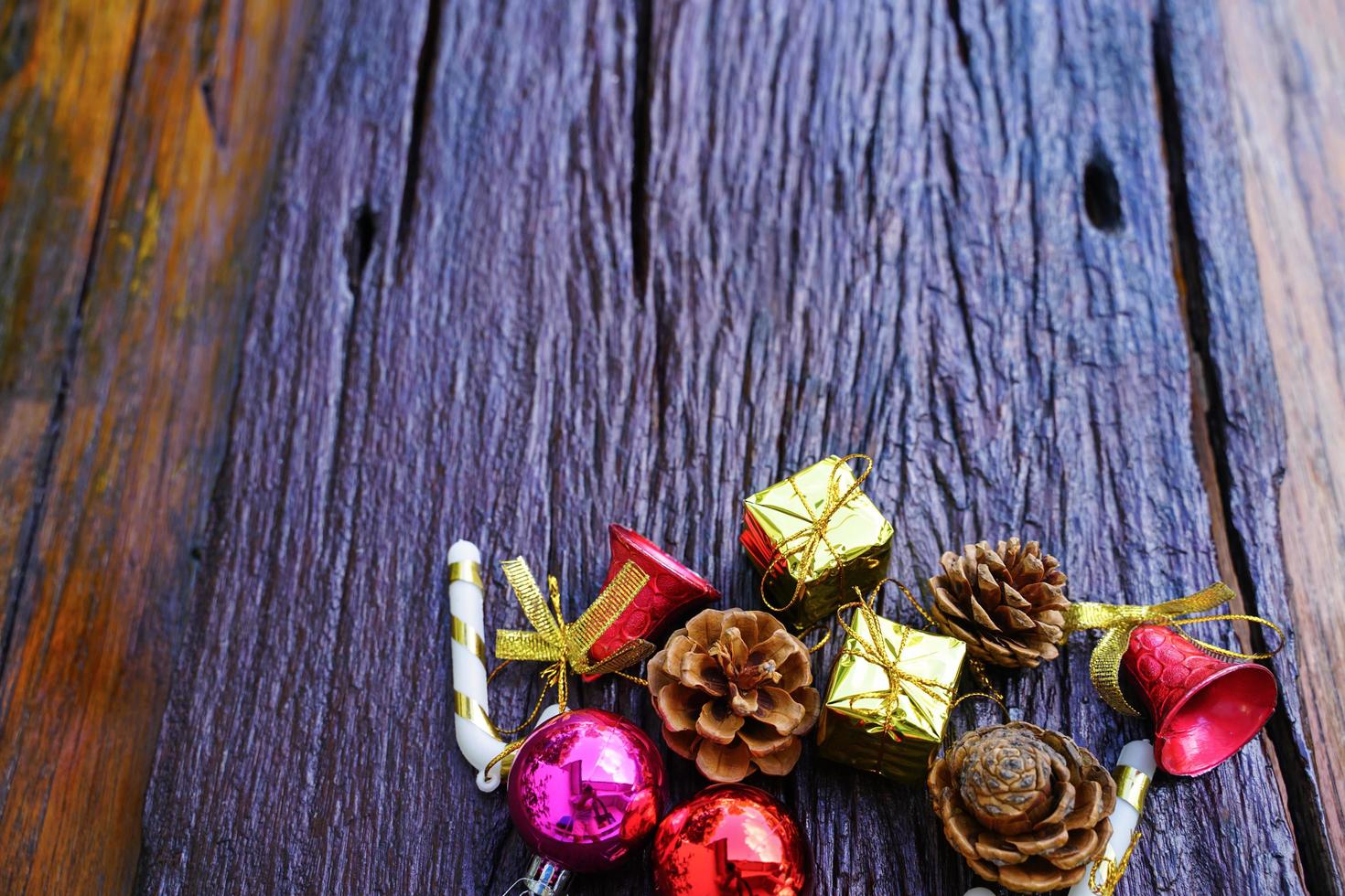 New Year and Christmas gift themed decorations on wooden background, consisting of a golden gift box.  shiny colored balls  Dried pine cones and small bells  free space for design photo