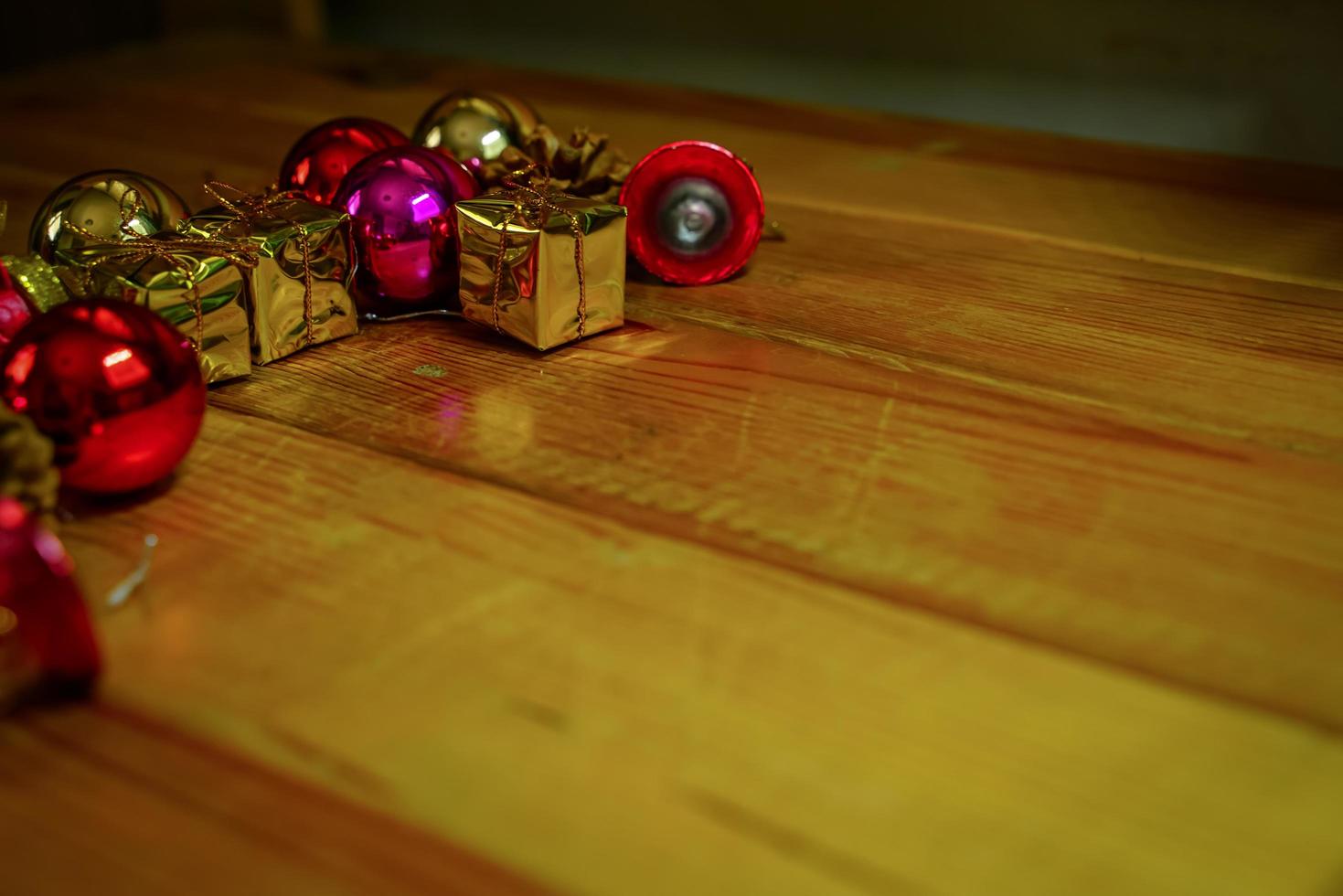 New Year and Christmas gift themed decorations on wooden background, consisting of a golden gift box.  shiny colored balls  Dried pine cones and small bells  free space for design photo