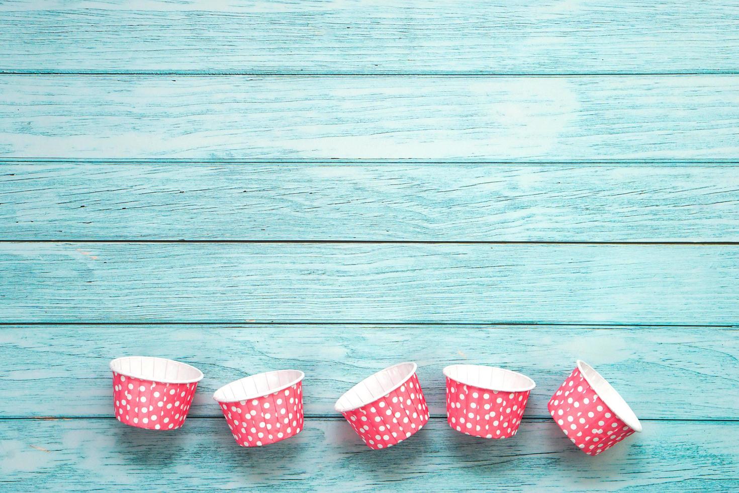 Pink polka dot cupcake cases on blue wooden floor. Material for baking. photo