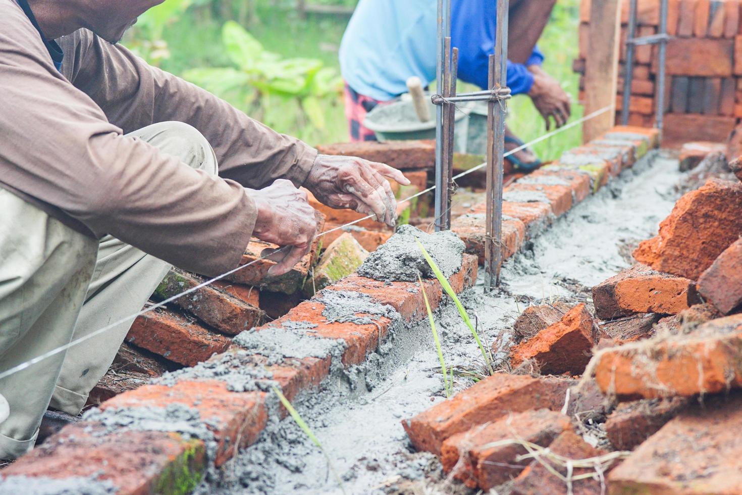 trabajadores de la construcción instalan ladrillos y cemento de hileras de ladrillos en paredes exteriores foto