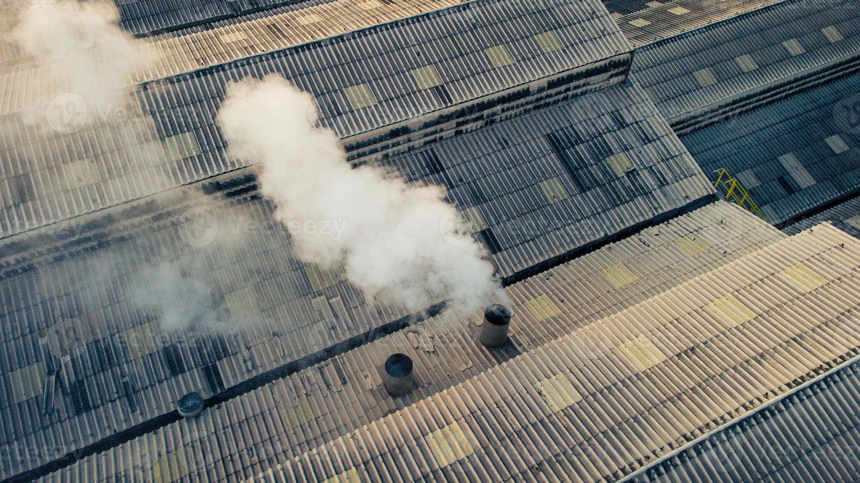 Los humos tóxicos se propagan desde el techo de una planta industrial. Las plantas industriales emiten grandes cantidades de humo de las fábricas durante la producción. que crea la contaminación del aire para el mundo. foto