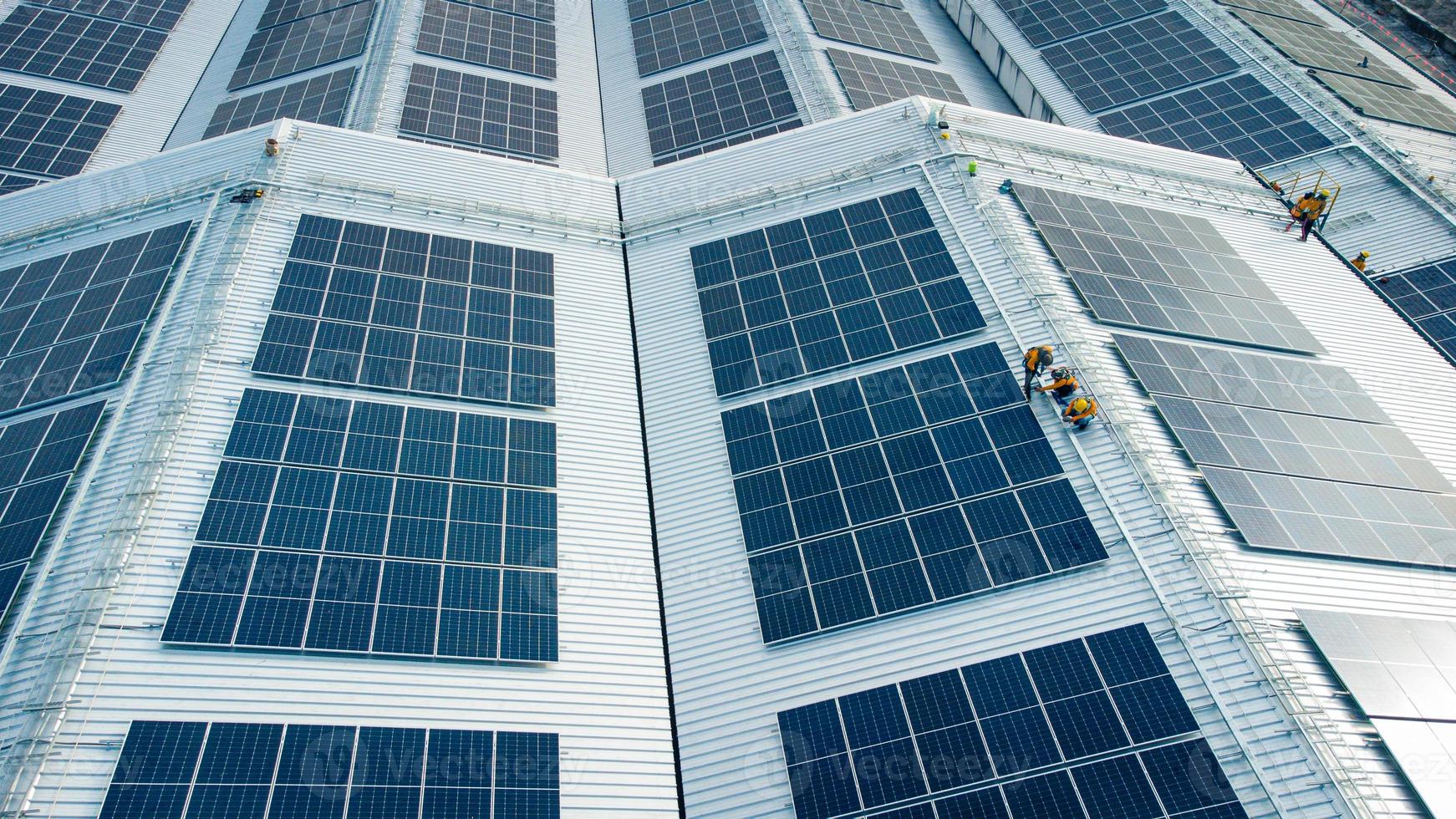 Fly over unidentified Engineering set up a Solar cell on the roof of a large industrial factory. Solar roofs are generating renewable energy for the industry. photo