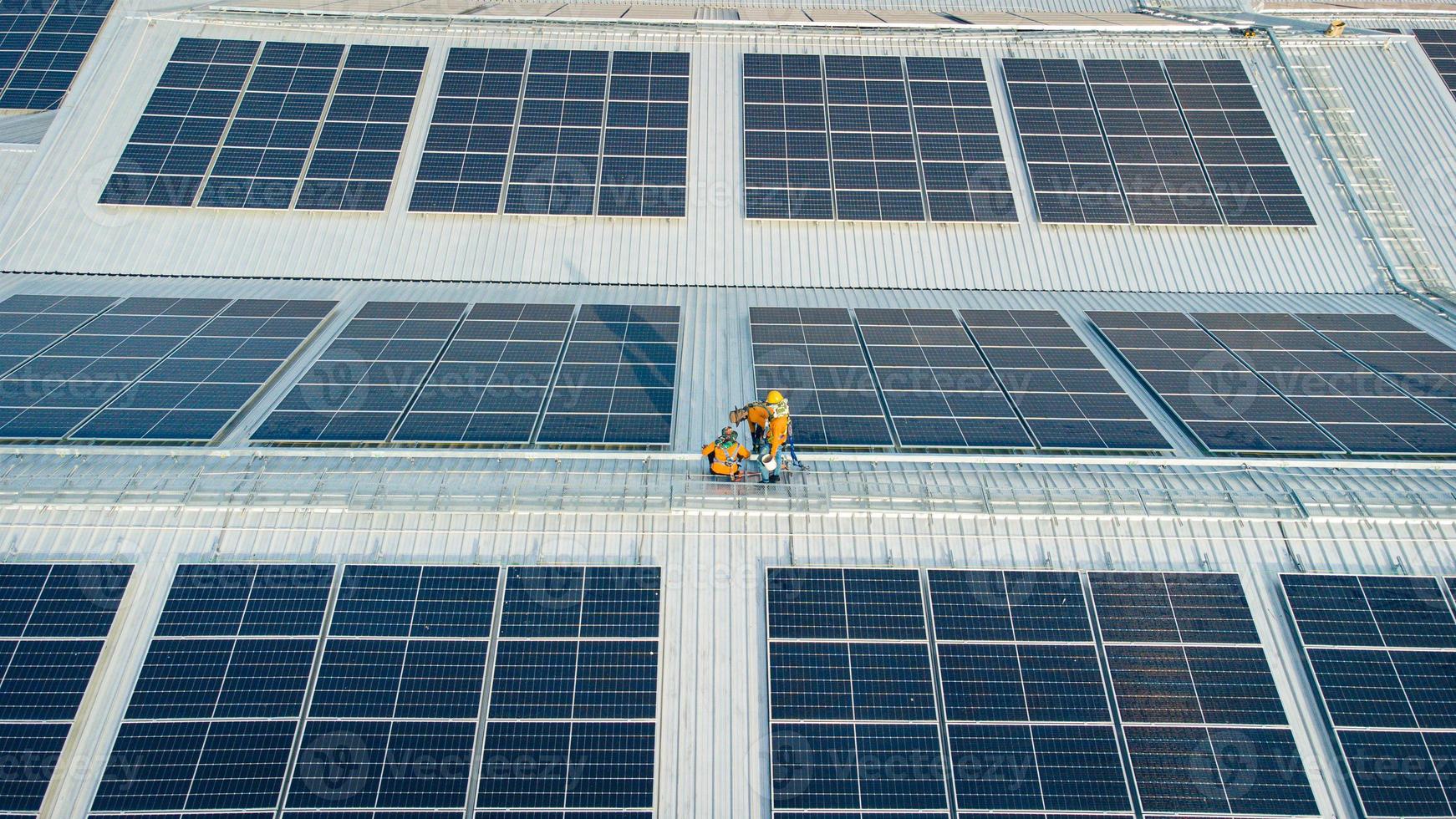 Fly over unidentified Engineering set up a Solar cell on the roof of a large industrial factory. Solar roofs are generating renewable energy for the industry. photo
