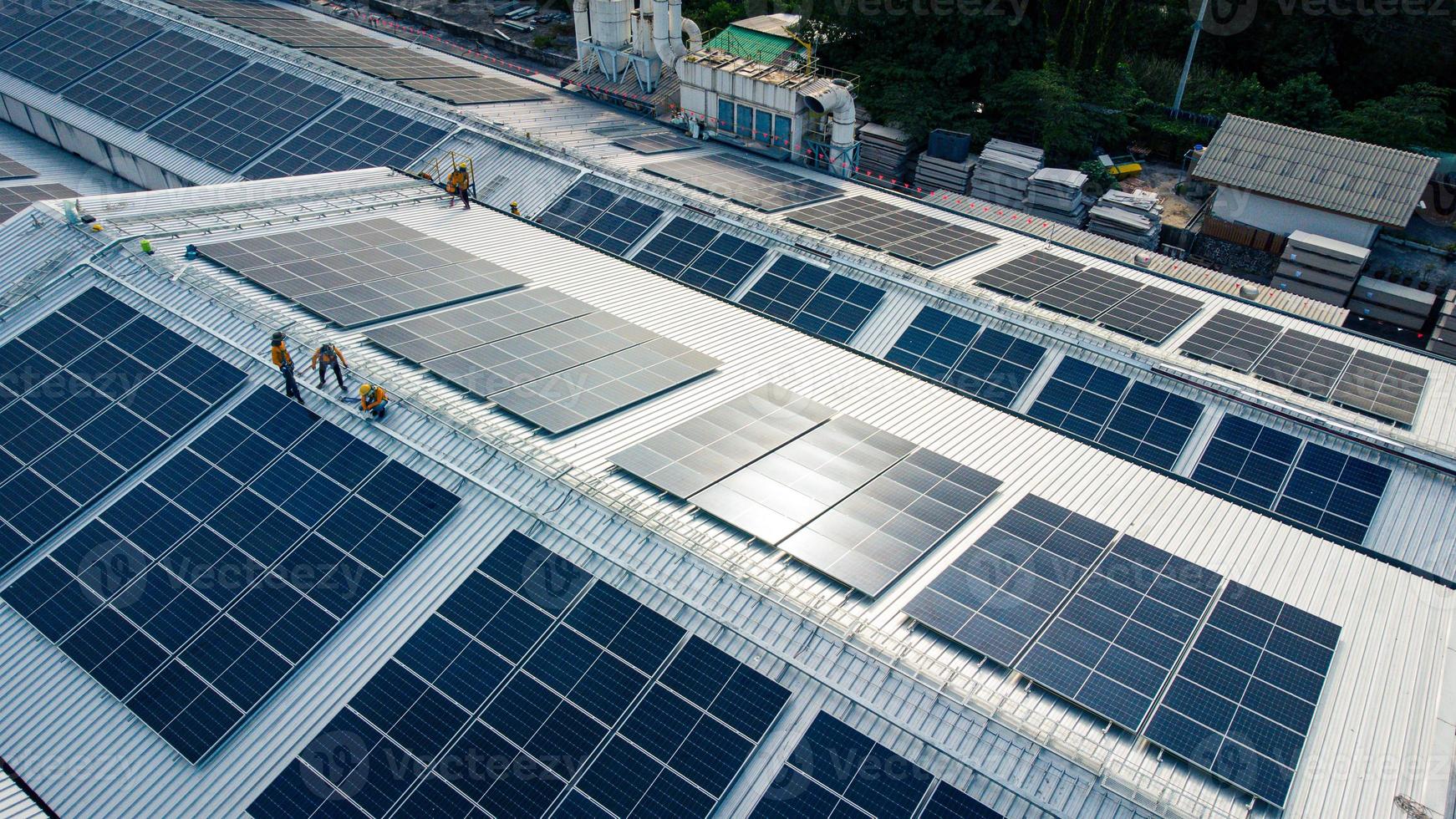 Fly over unidentified Engineering set up a Solar cell on the roof of a large industrial factory. Solar roofs are generating renewable energy for the industry. photo