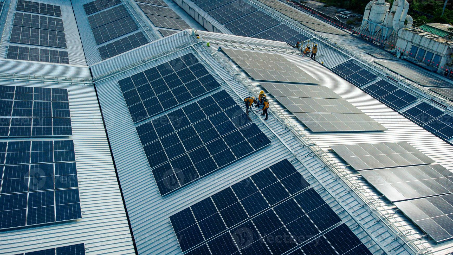 Fly over unidentified Engineering set up a Solar cell on the roof of a large industrial factory. Solar roofs are generating renewable energy for the industry. photo