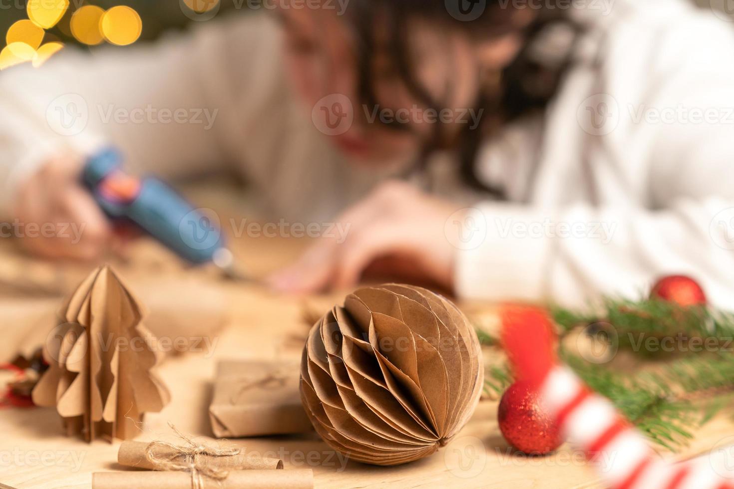 girl makes Christmas tree decorations out of paper with her own hands. step-by-step instruction photo