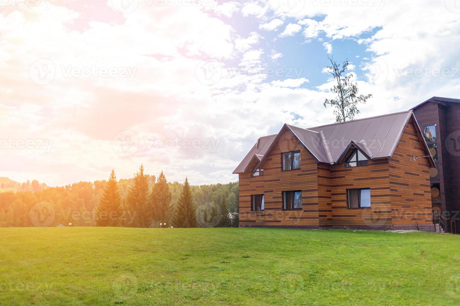 Two-storey wooden cottage with windows nature with a green lawn. Sale or purchase of new houses. A hotel for tourists. photo