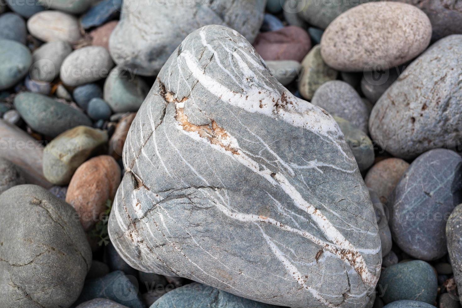 grandes piedras de diferentes formas en el primer plano de la orilla del río. hay muchas piedras pequeñas cerca. foto