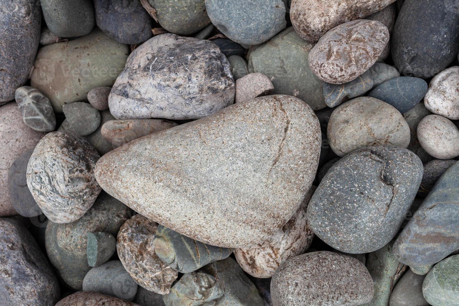Large stones of different shapes on the riverbank close-up. there are a lot of small stones nearby. photo