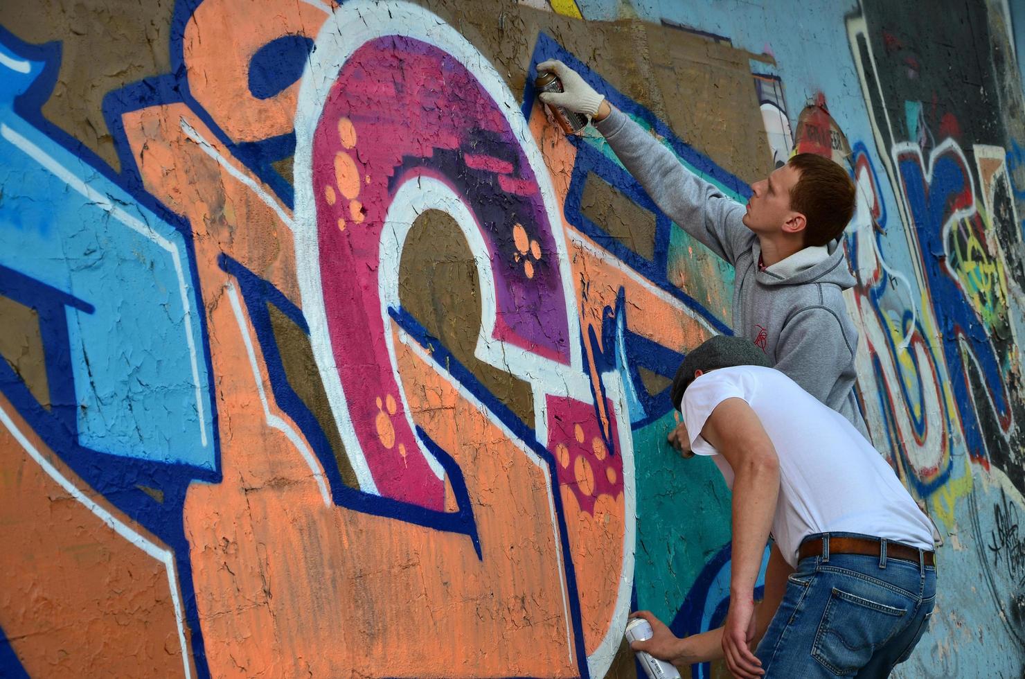 KHARKOV. UKRAINE - MAY 2, 2022 Festival of street arts. Young guys draw graffiti on an old concrete walls in the center of the city. The process of painting on walls with aerosol spray cans photo