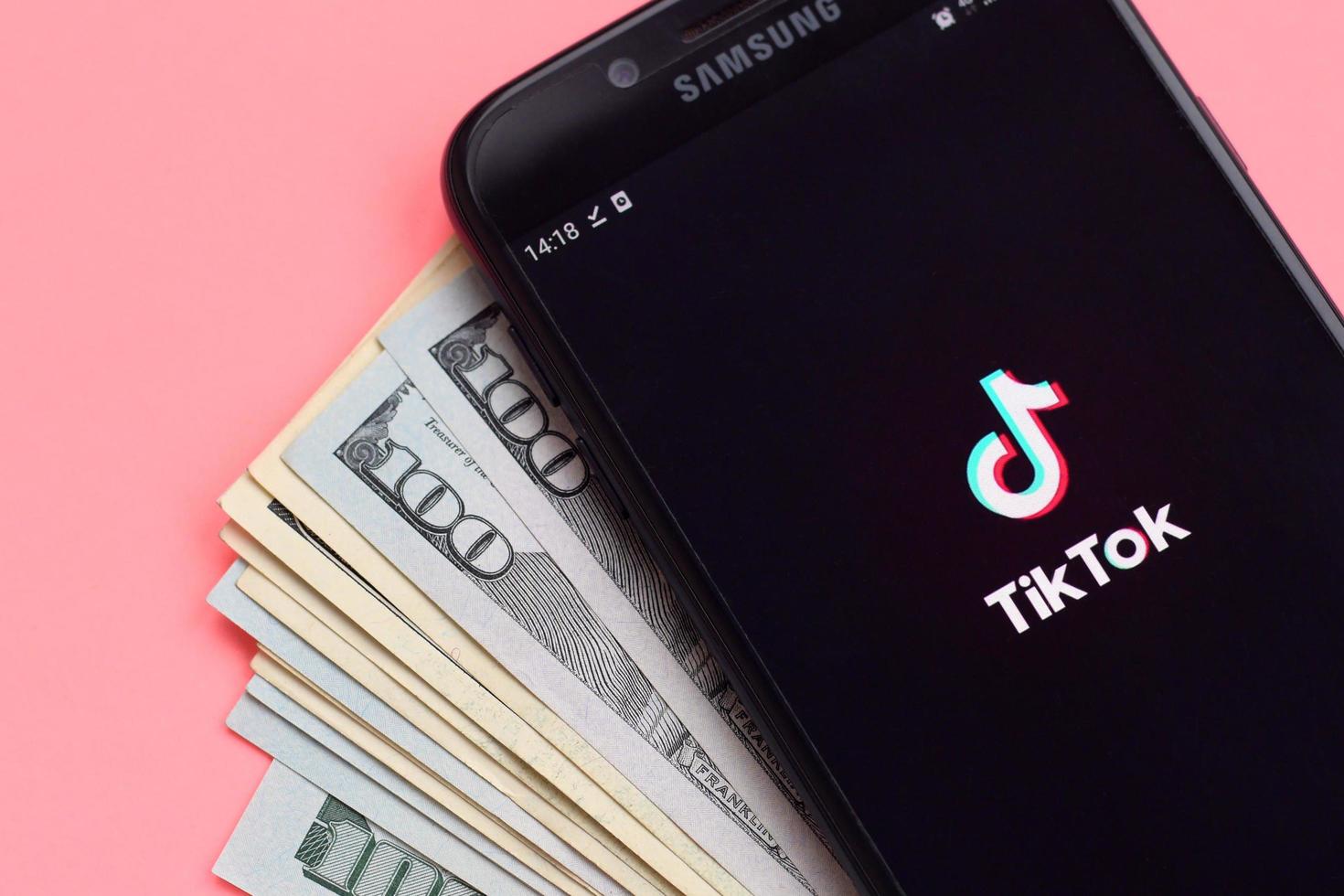 Jarkov. ucrania - 17 de mayo de 2022 aplicación tiktok en la pantalla del teléfono inteligente samsung y billetes de dólar. tiktok es un popular servicio de redes sociales para compartir videos propiedad de bytedance foto