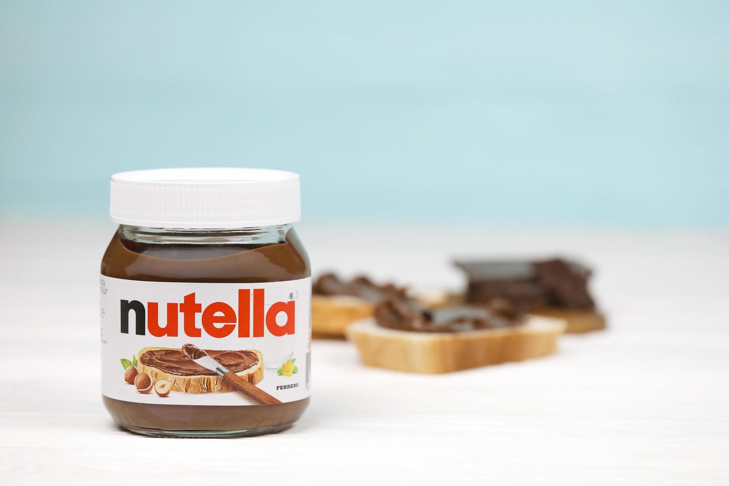 KHARKOV, UKRAINE - MAY 5, 2022 Nutella glass can and spread on freshly baked bread. Nutella is manufactured by Italian company Ferrero first introduced in 1964 photo