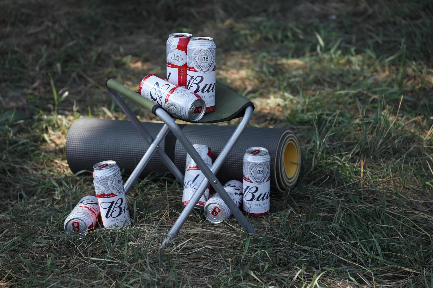 KHARKOV, UKRAINE - MAY 12, 2022 Few Cans of Budweiser Lager Alcohol Beer on fisherman chair outdoors. Budweiser is a Brand from Anheuser-Busch Inbev photo
