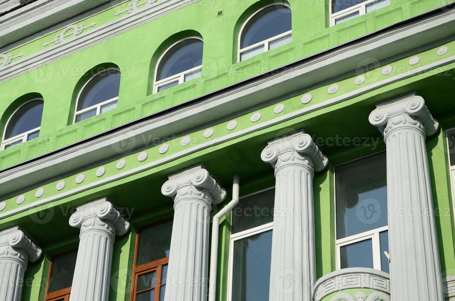 antiguo edificio restaurado de varias plantas con columnas antiguas, pintado de verde foto