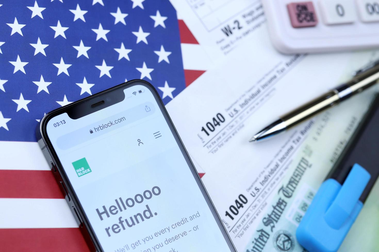 KHARKOV. UKRAINE - MAY 2, 2022 HR Block website on iPhone 12 pro screen with 1040 and w-2 paper tax forms on US flag photo