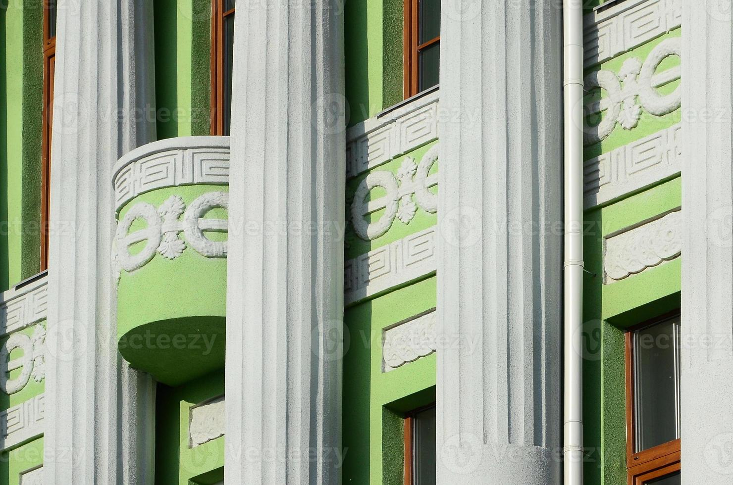 Restored old multi-storey building with antique columns, painted in green photo