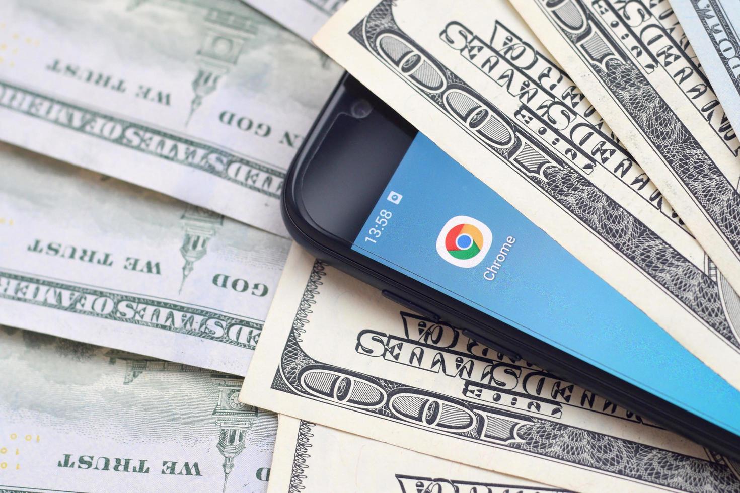 KHARKOV, UKRAINE - MAY 3, 2022 Smartphone screen with Google chrome app and lot of hundred dollar bills. Business and social networking concept photo
