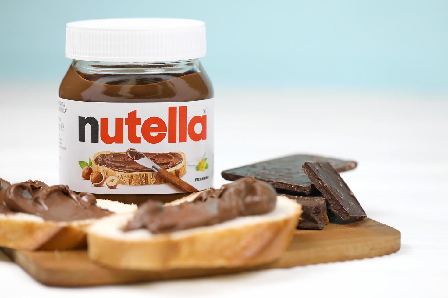 KHARKOV. UKRAINE - MAY 17, 2022 2020 Nutella glass can and spread on freshly baked bread. Nutella is manufactured by Italian company Ferrero first introduced in 1964 photo