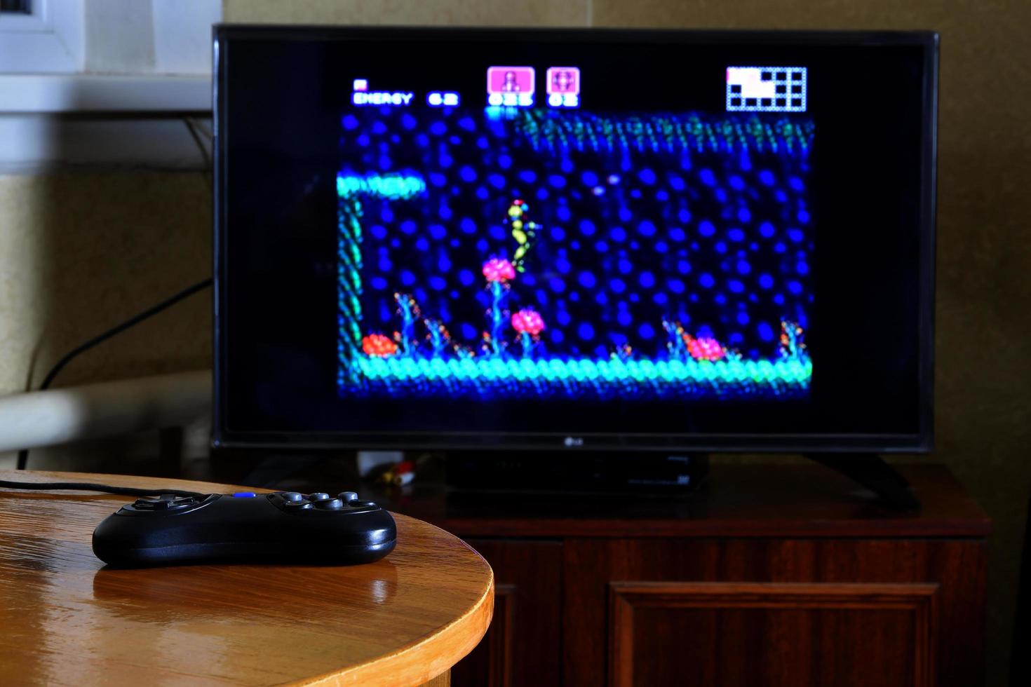 KHARKOV, UKRAINE - MAY 12, 2022 Sega mega drive video game controller on table with Super Metroid game on display photo