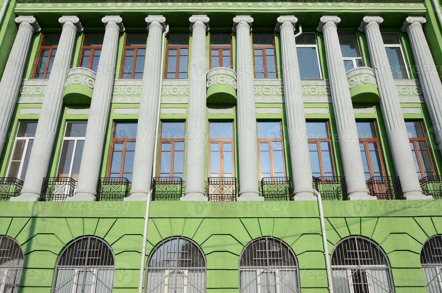 Restored old multi-storey building with antique columns, painted in green photo