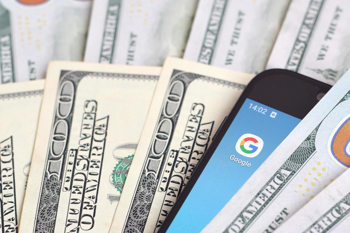 KHARKOV, UKRAINE - MAY 12, 2022 Smartphone screen with Google app and lot of hundred dollar bills. Business and social networking concept photo