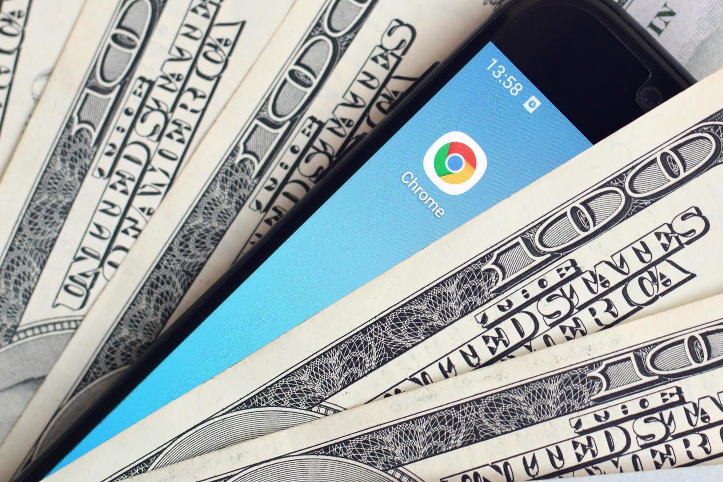 KHARKOV, UKRAINE - MAY 12, 2022 Smartphone screen with Google chrome app and lot of hundred dollar bills. Business and social networking concept photo