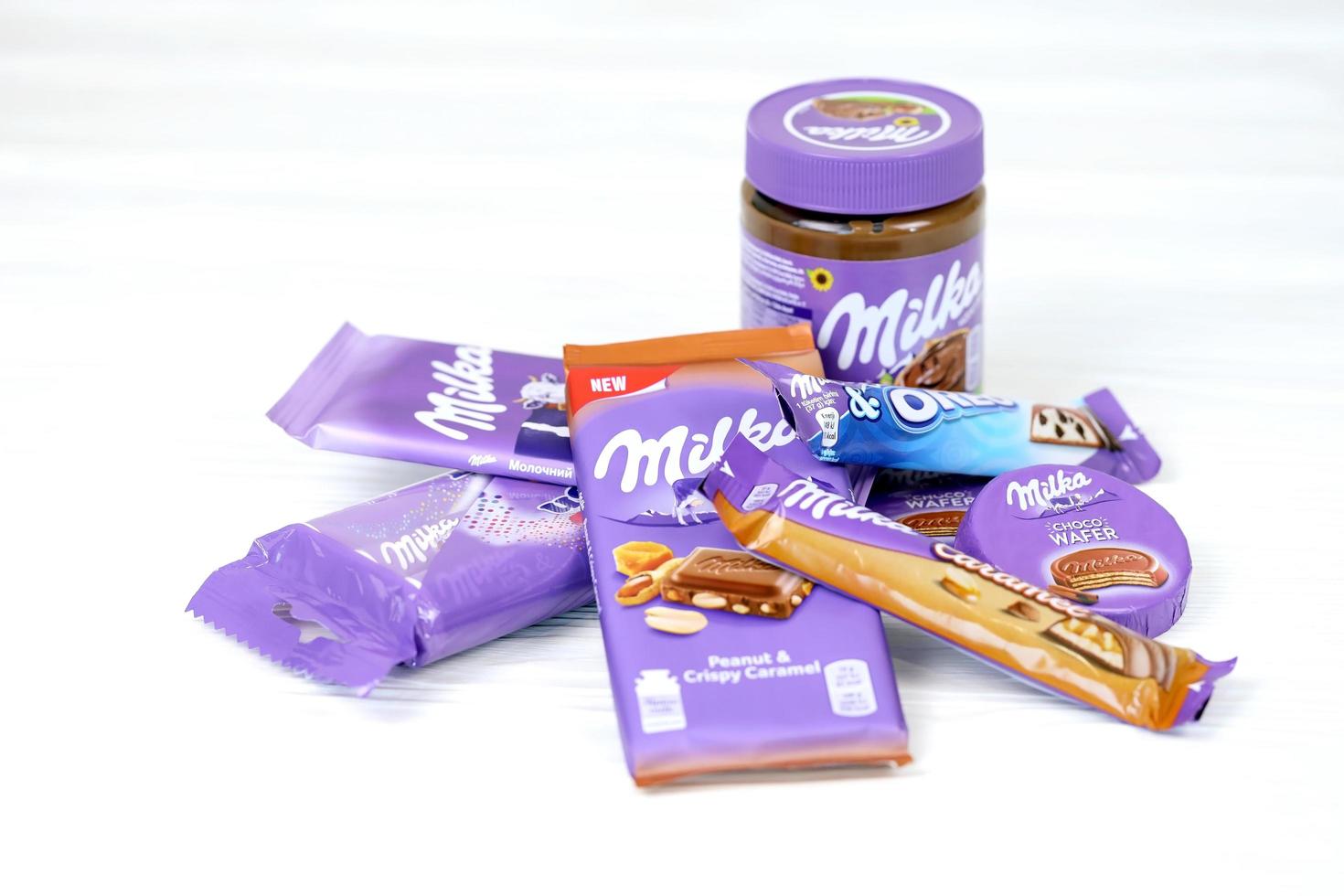 kharkov, ucrania - 12 de mayo de 2022 productos de chocolate milka con diseño de envoltura de color lila clásico en mesa blanca foto