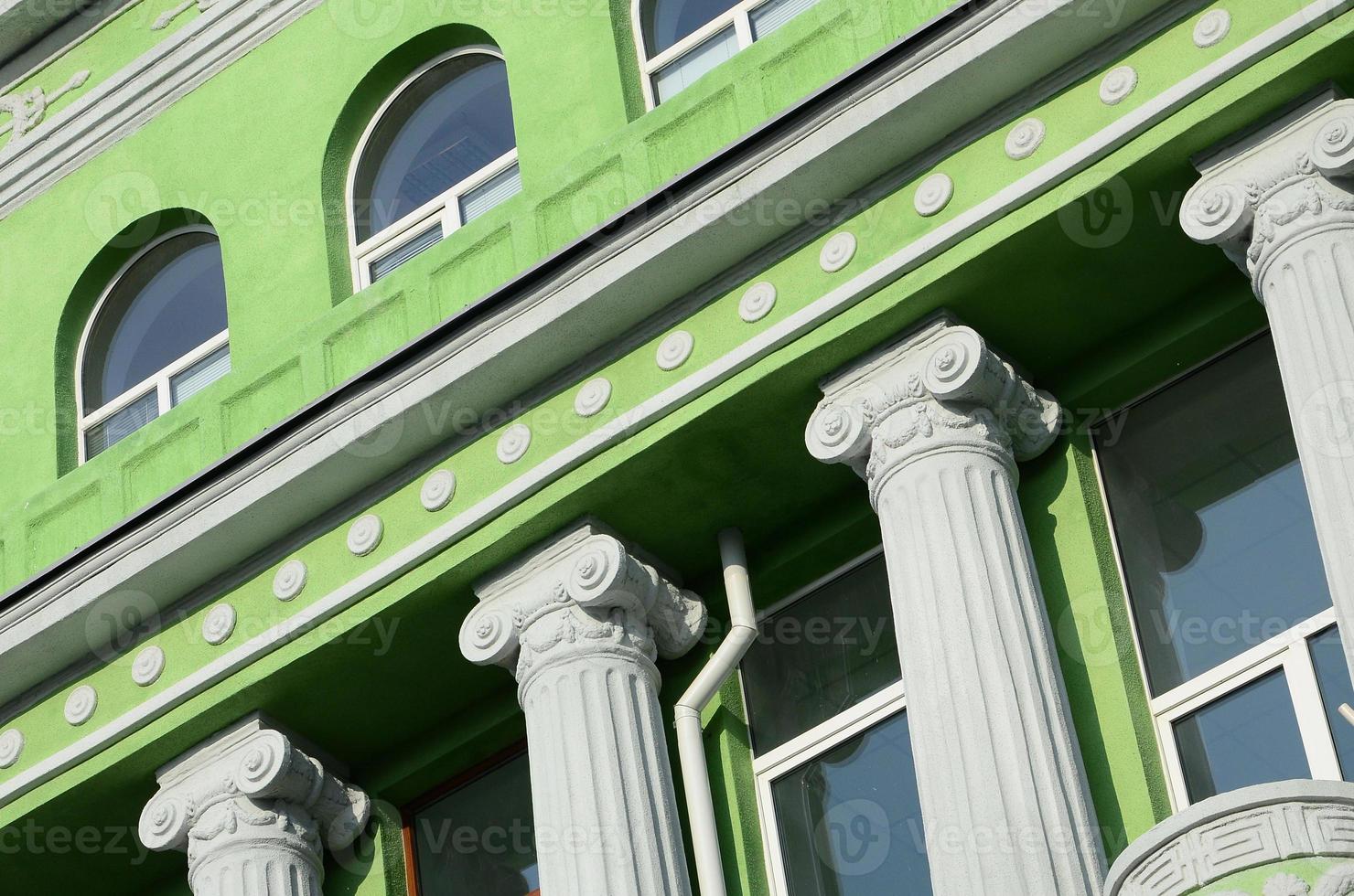 Restored old multi-storey building with antique columns, painted in green photo