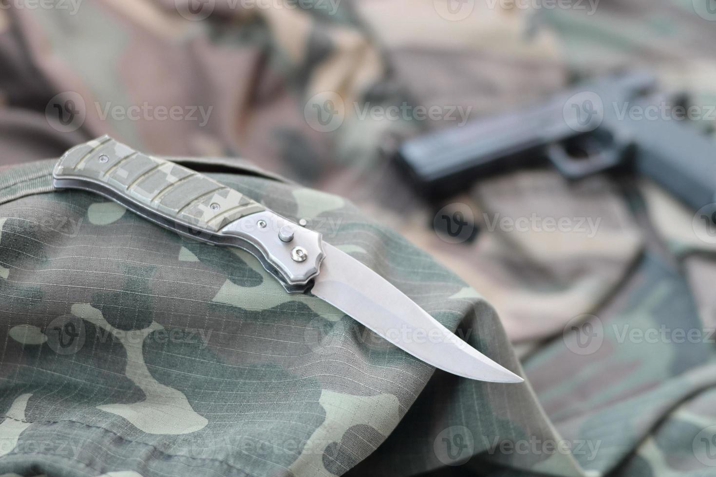 Tactical knife and pistol lie on camouflage green fabric photo