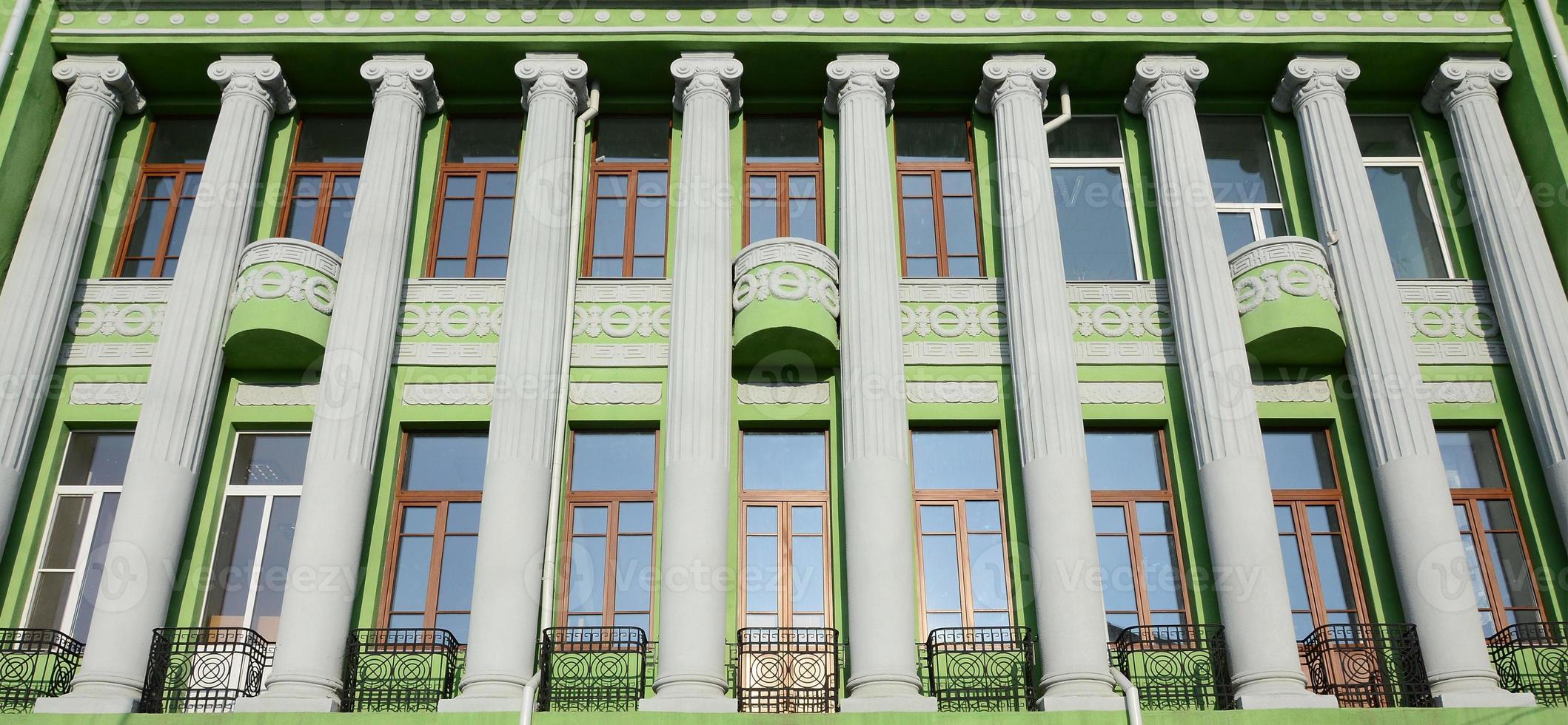 Restored old multi-storey building with antique columns, painted in green photo