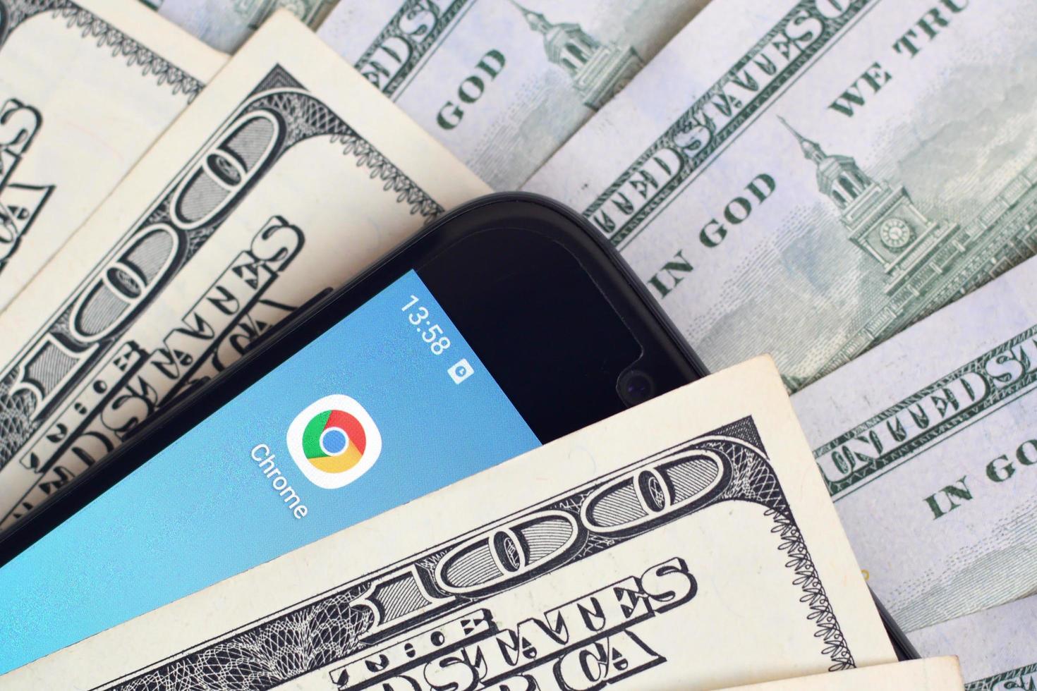 KHARKOV, UKRAINE - MAY 12, 2022 Smartphone screen with Google chrome app and lot of hundred dollar bills. Business and social networking concept photo