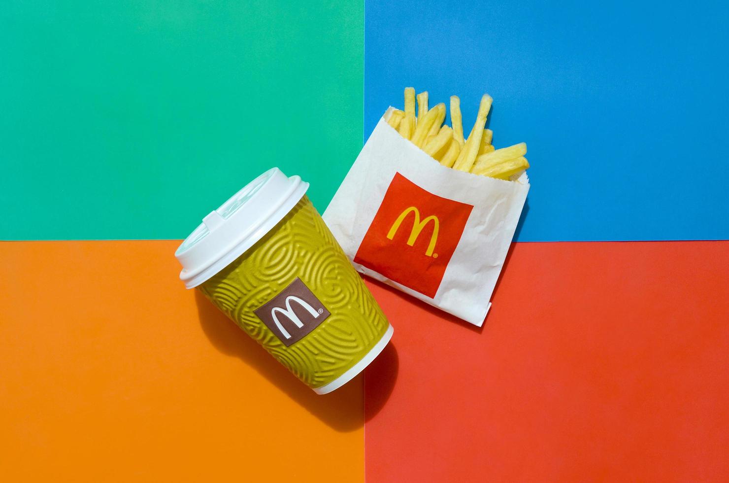 KHARKOV, UKRAINE - MAY 12, 2022 McDonald's French fries in small paperbag and coffee cup on bright colored background photo