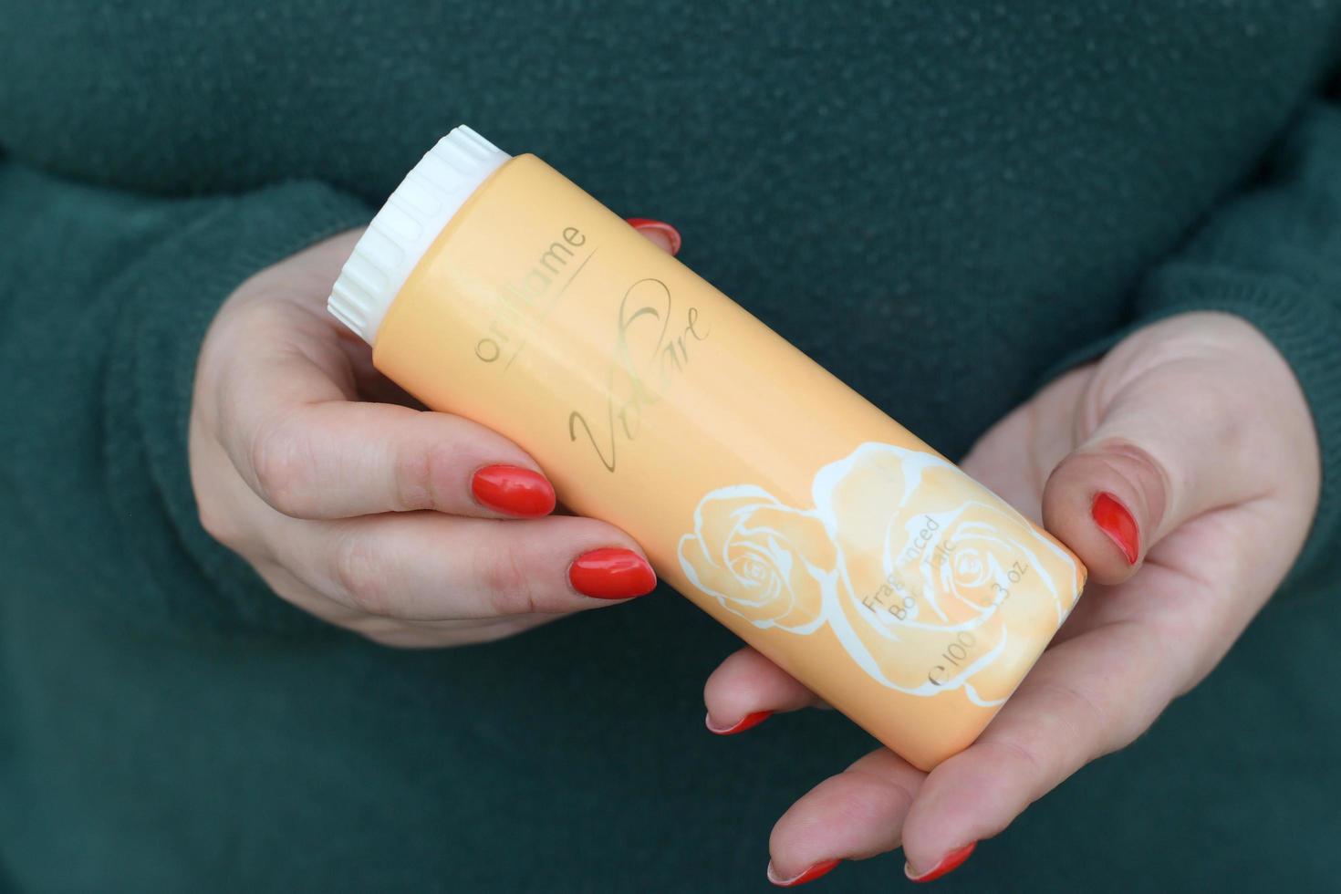 KHARKOV, UKRAINE - MAY 3, 2022 Young girl holds Oriflame Volare fragranced body talc. Oriflame Holding AG is a multi-level marketing cosmetics company founded in Sweden in 1967 photo