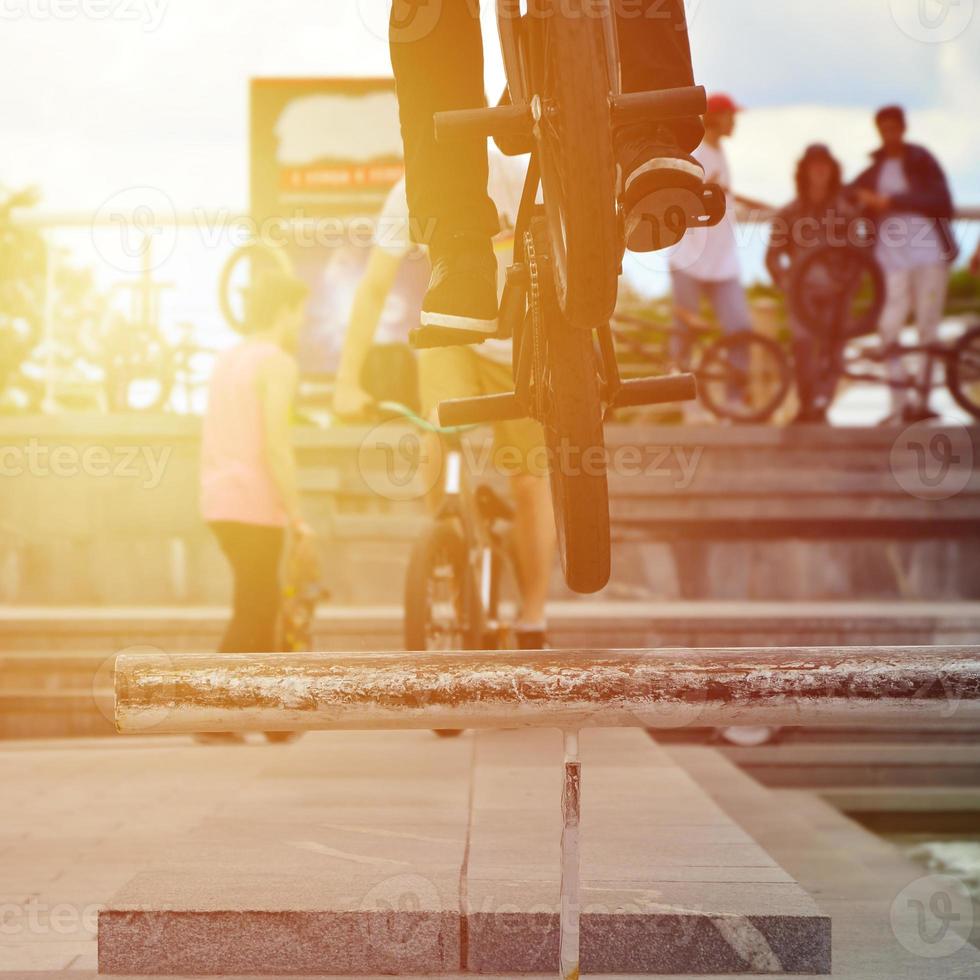 A cyclist jumps over a pipe on a BMX bike. A lot of people with bicycles in the background. Extreme sports concept photo