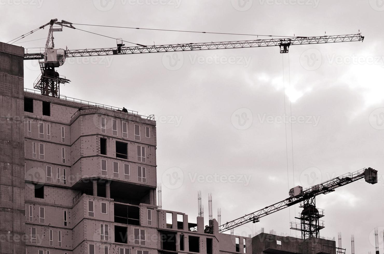 grúas altas de trabajo dentro del lugar con edificios altos en construcción contra un cielo azul claro. Grúa y construcción de progreso de trabajo. tono retro foto