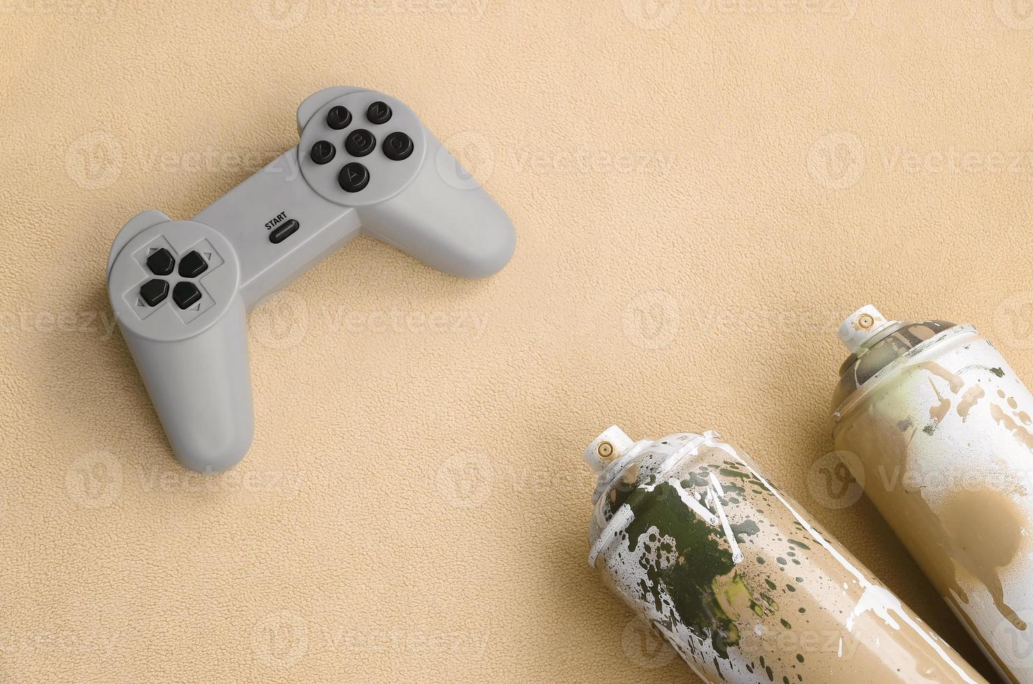 Teenagers and youth lifestyle concept. Joystick and two spray cans lies on the blanket of furry orange fleece fabric. Controllers for video games and paint cans on a plush fleece material background photo