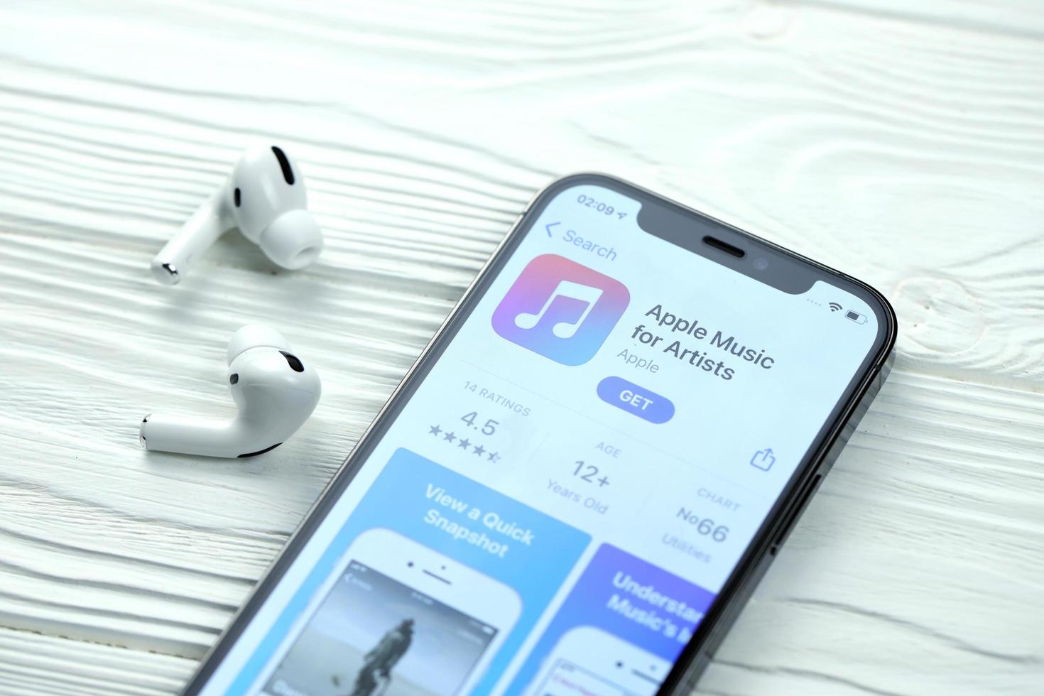 KHARKOV. UKRAINE - MAY 2, 2022 Apple music for artists icon and application from App store on iPhone 12 pro display screen with airpods pro on white table photo