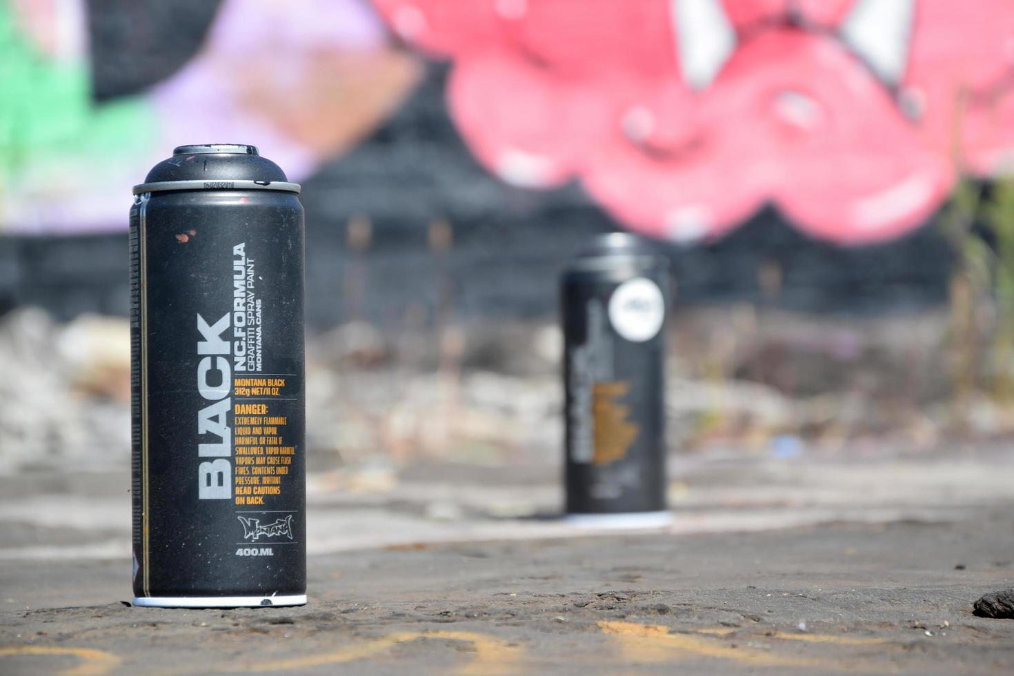 KHARKOV. UKRAINE - MAY 2, 2022 Used Montana black aerosol spray cans against graffiti paintings. MTN or Montana-cans is manufacturer of high pressure spray paint goods photo