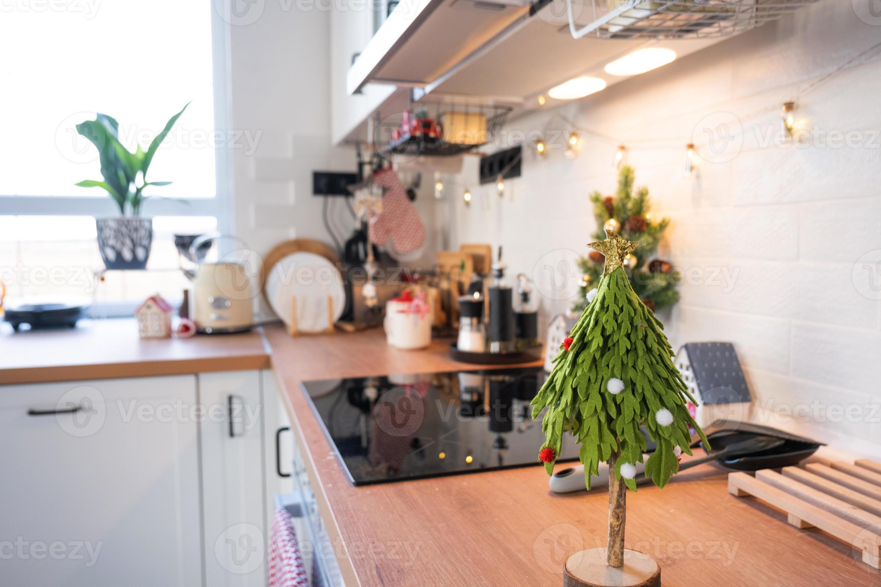 Christmas kitchen decor - preparation for a family holiday, fairy light,  Christmas tree, red ornament, funny deer on cabinets, stove. Mood of  celebration, eve, New year 13940917 Stock Photo at Vecteezy