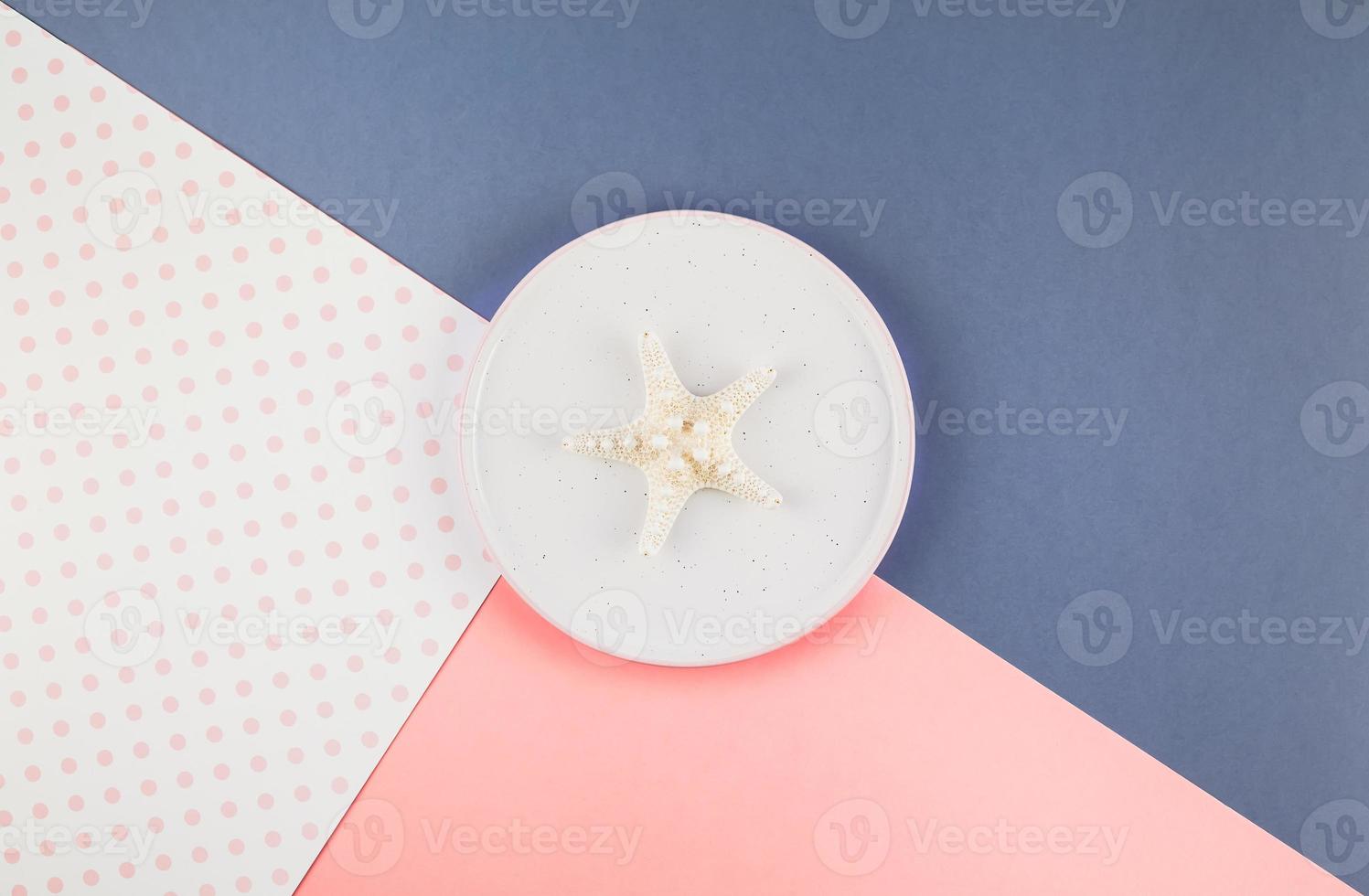 Plate with seashells on color paper background photo