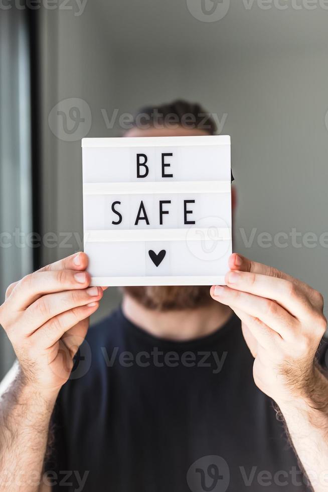 hombre sosteniendo una caja de luz con el texto esté seguro en su mano foto