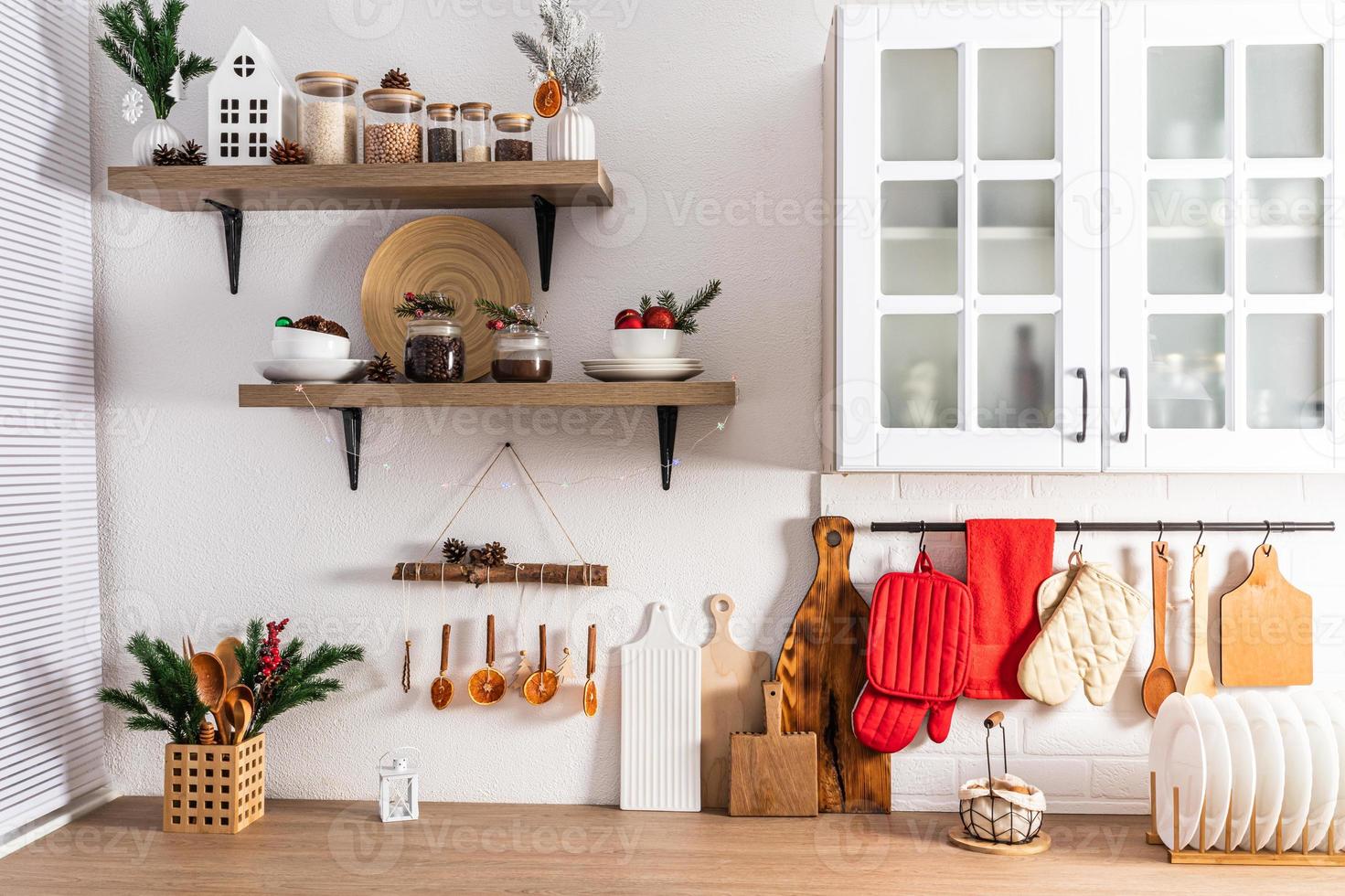 The front view of part of a modern white kitchen and open shelves decorated for New Year in traditional colors. Eco items and homemade decorations. photo