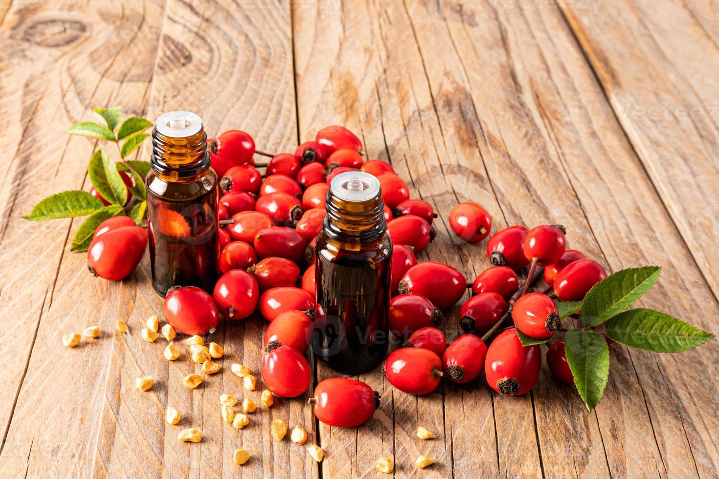 two glass medical bottles with a dropper with essential oil of rosehip seeds for medical use. spa treatments. relaxation. wooden background. photo