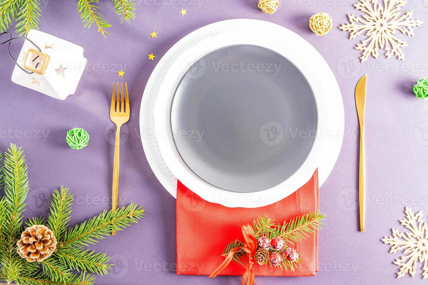 top view of the festive empty plate on the New Year's or Christmas table with a spruce branch, a lantern and confetti. A blank layout for your food. photo