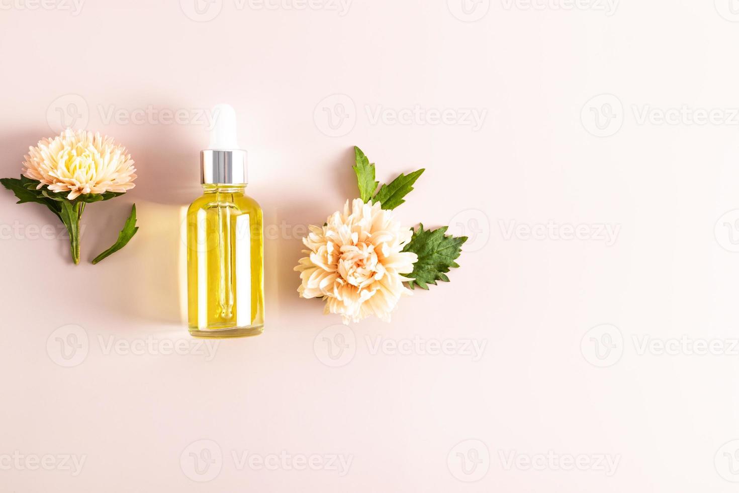 botella cosmética con una pipeta sobre un fondo pastel con flores de aster. cosmética natural. Productos para el cuidado de la piel. diseño. vista superior. un espacio de copia. foto