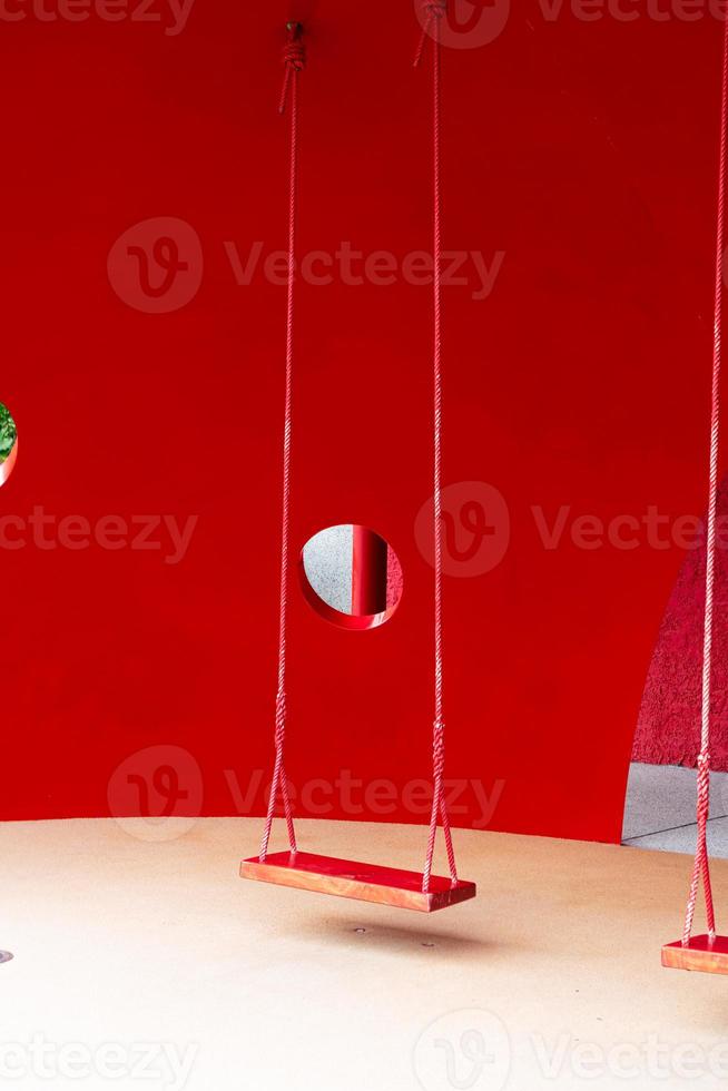 red swing with red background photo