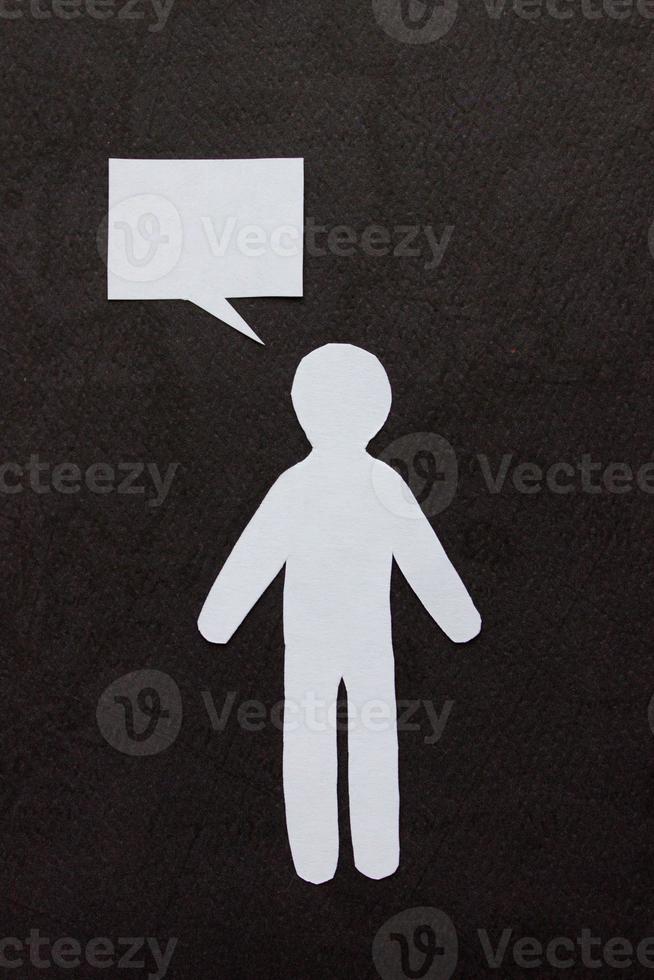 Silhouette of man cut out of white paper. With speech-bubble. In the center of photo on a black background